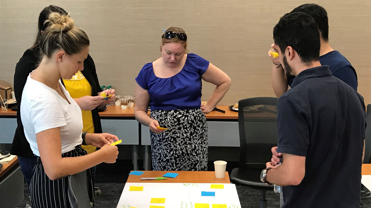 Teammates sort user feedback into an affinity map diagram during a Design Bloc collaboration with the Excel certificate program. 