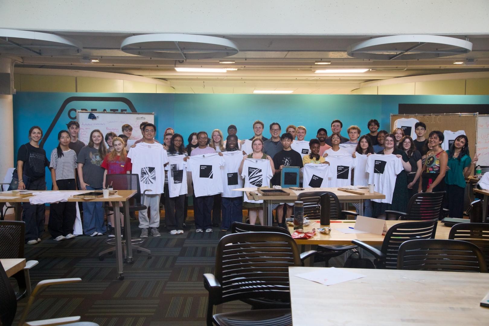 Group of students holding white t-shirts with printed graphics
